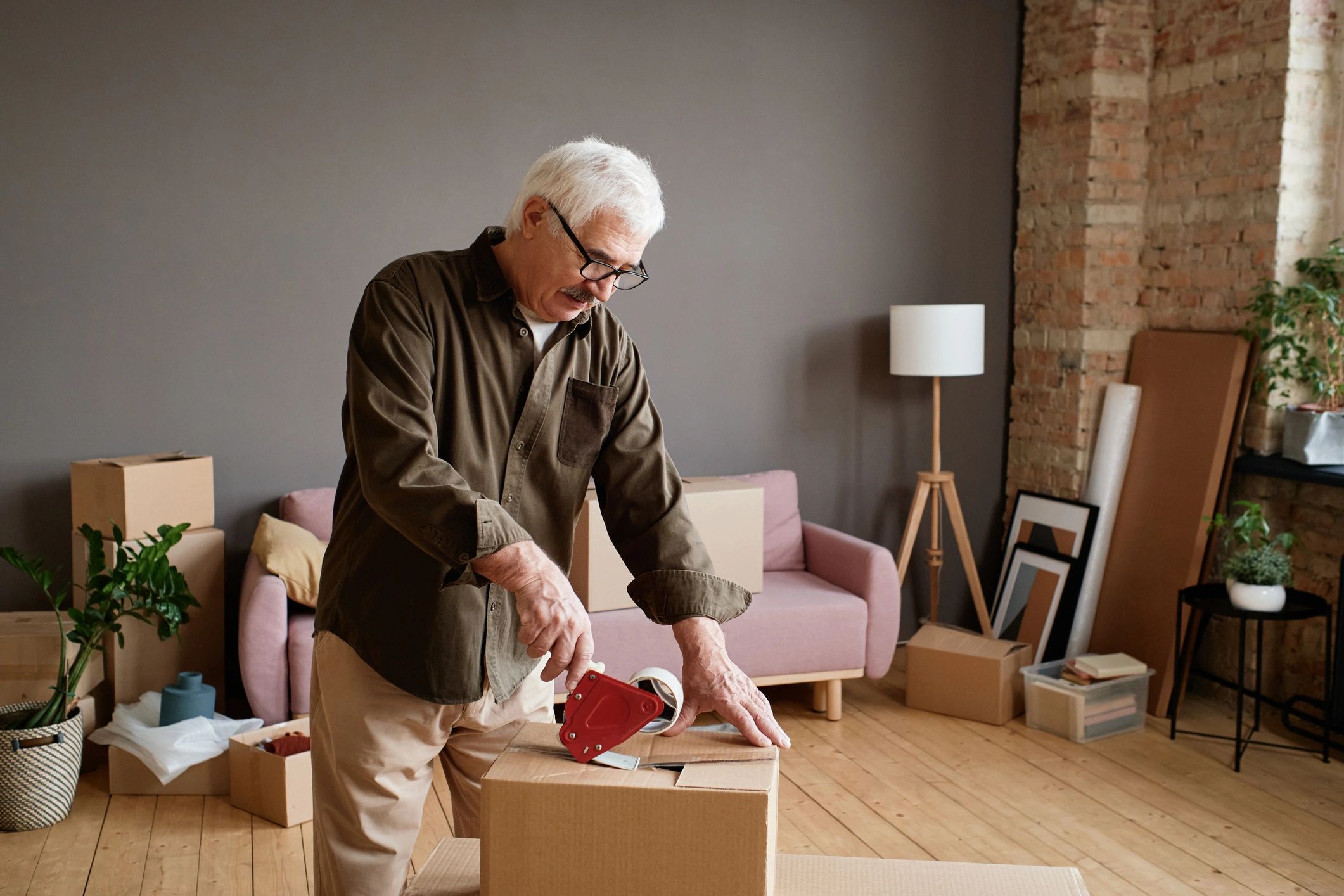 Approachable older man in a Mr Odd Jobs t-shirt helping with practical home tasks and moving boxes
