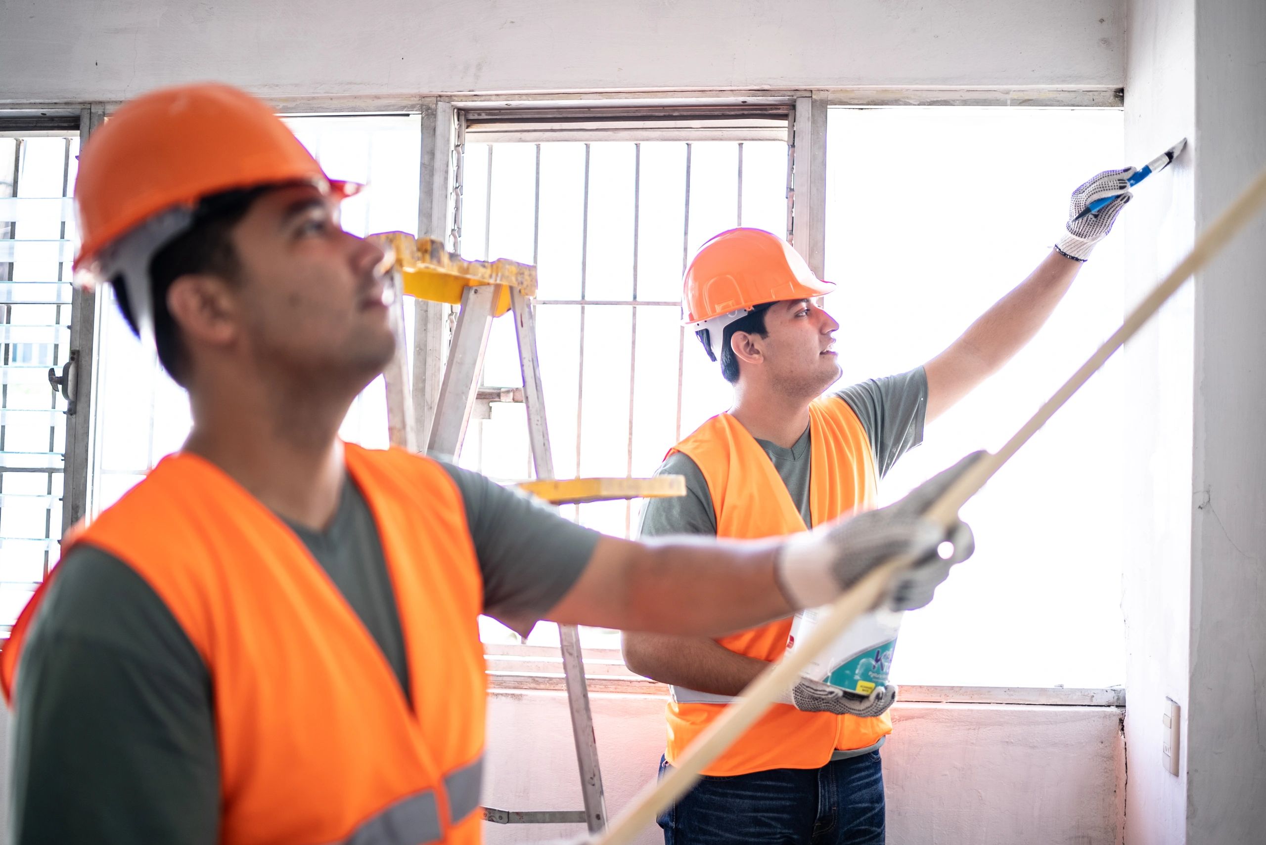 Two people painting an interior wall