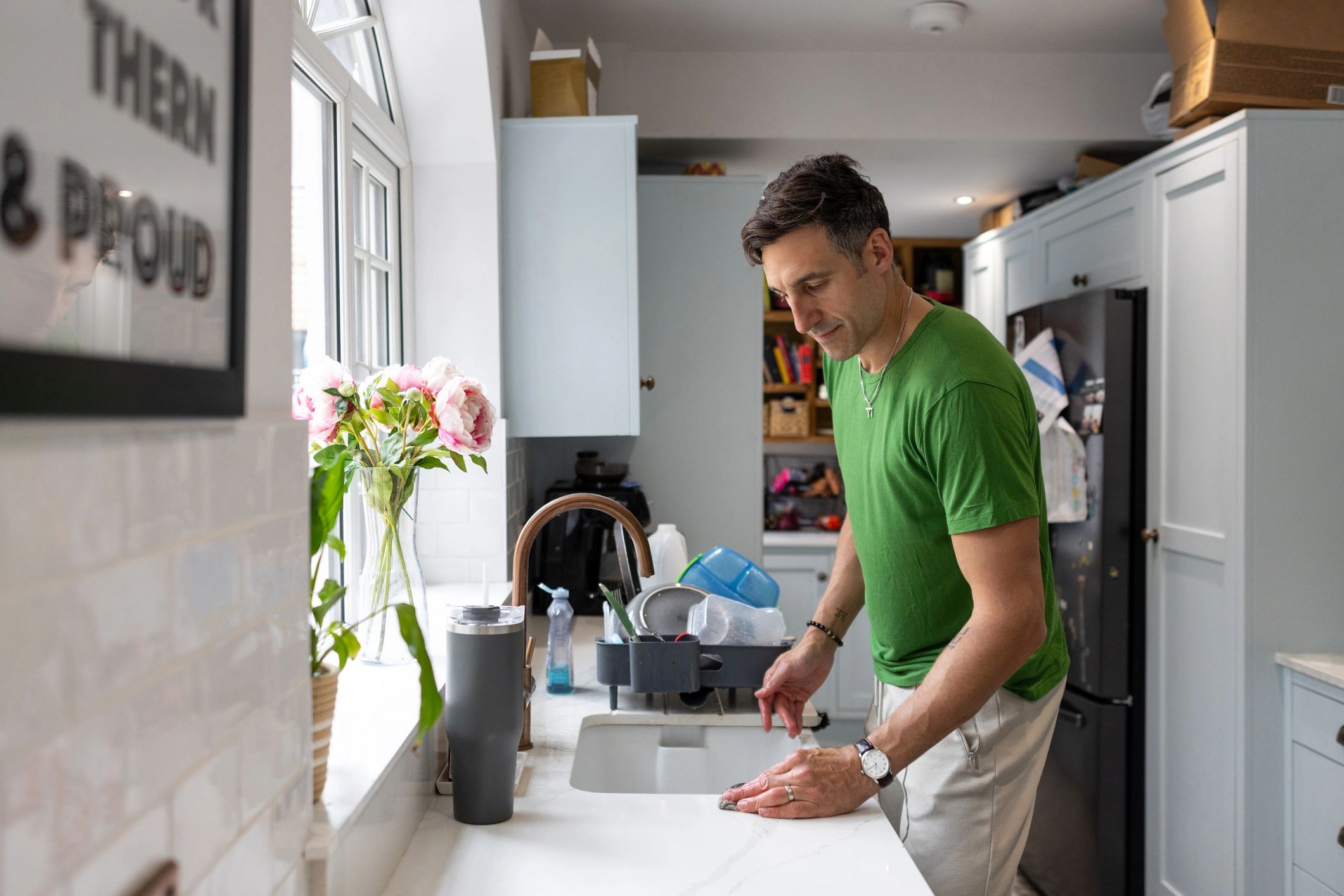 Approachable older handyman in a Mr Odd Jobs t-shirt doing a simple household task in a bright kitchen
